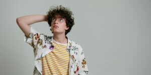 man in a floral polo thinking while his hand is on his head