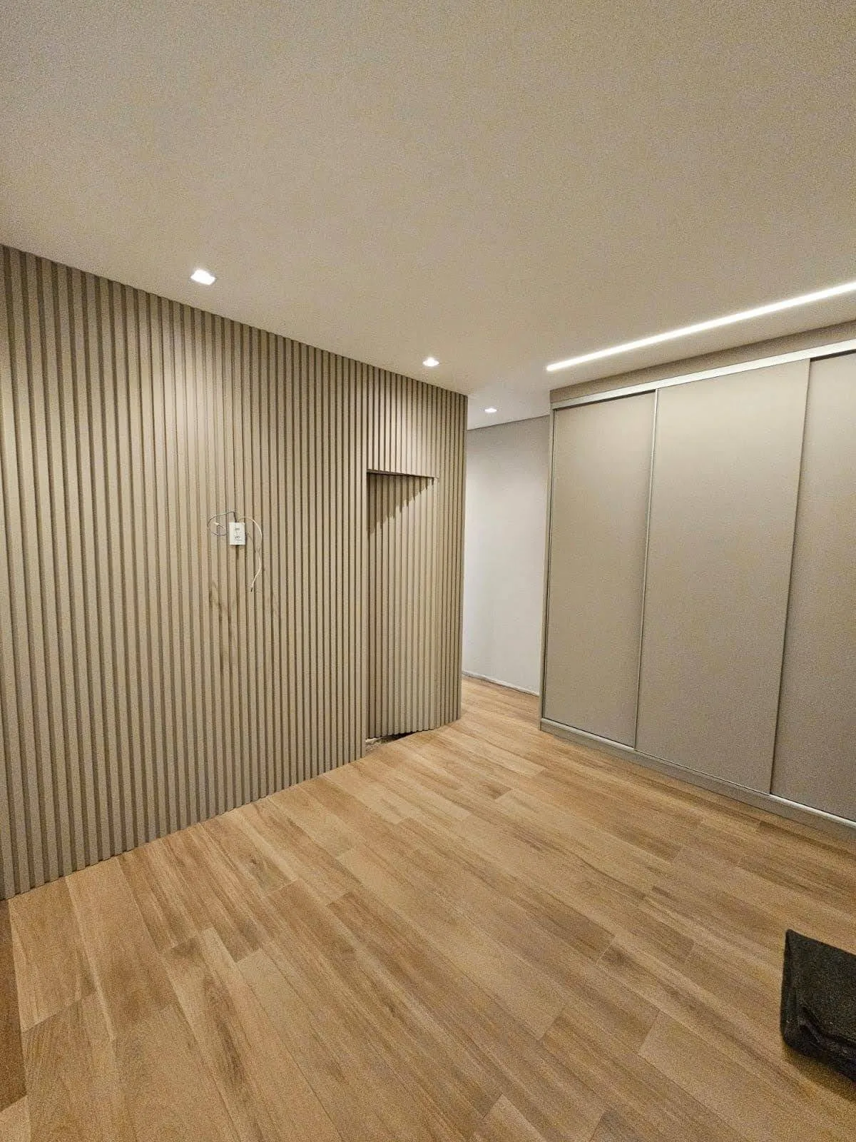 Quarto de casal planejado com painel e porta de banheiro mimetizada integrada ao painel, executado pela Amazonas Planejados em Conselheiro Lafaiete