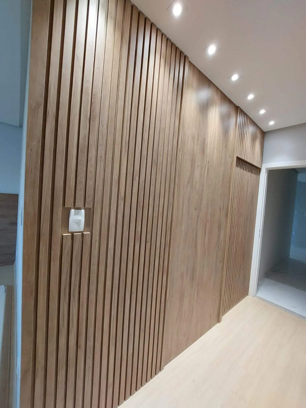 Painel ripado planejado na entrada do closet, Condomínio Granja das Hortênsias, Conselheiro Lafaiete, executado pela Amazonas Planejados