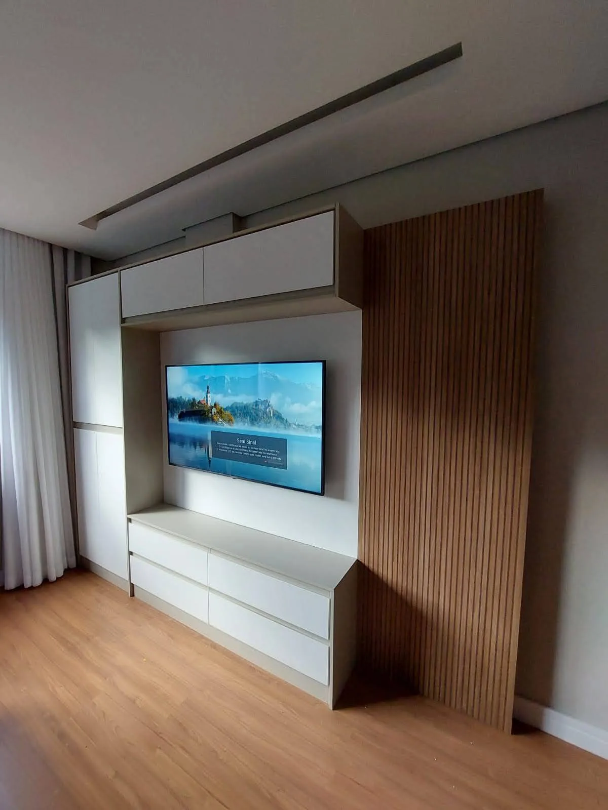 Quarto de casal planejado com painel de TV e armário lateral ocultando coluna estrutural, Bairro Quinta das Flores, Conselheiro Lafaiete, executado pela Amazonas Planejados